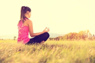 Pratik Yoga bir çayır mercek parlaması ile günbatımı, görüntü üzerinde genç atletik kadın