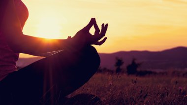 Pratik Yoga bir çayır, günbatımı, siluet üzerinde genç atletik kadın