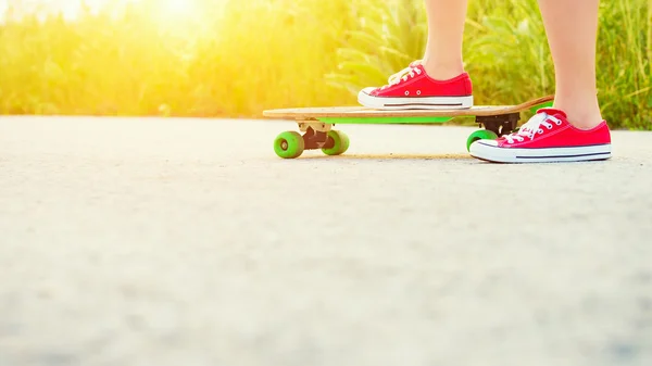 Anonymous teenage girl with skateboard, image with sunflare — Stock Photo, Image