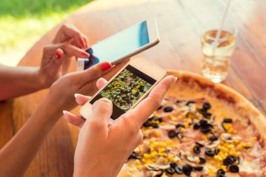 Pizza fotoğraf çekmek için akıllı telefonlar kullanan arkadaşlar