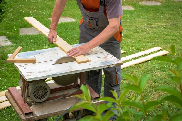 Carpenter working with electric buzz saw cutting wooden boards — Stock Photo, Image