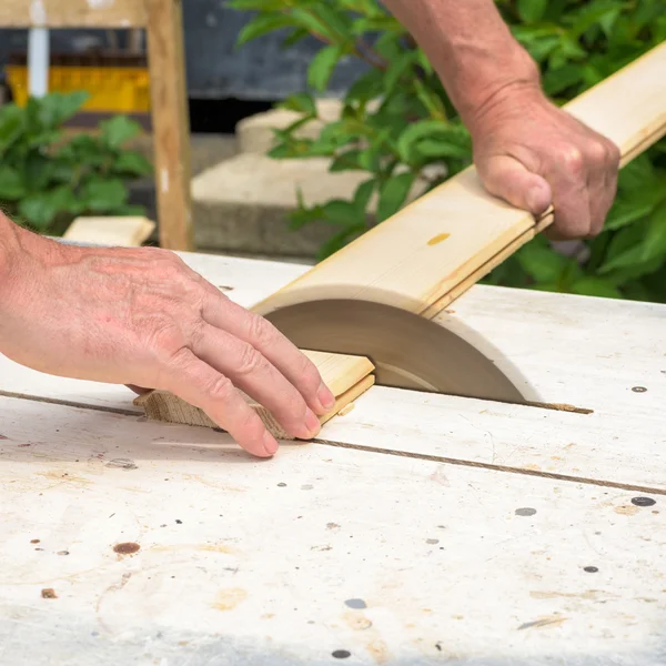 Carpintero trabajando con sierra eléctrica para cortar tableros de madera — Foto de Stock
