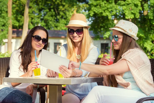 Kokteyller tatmak ve dijital tablet üzerinde kablosuz bağlantı kullanarak üç çekici kız — Stok fotoğraf