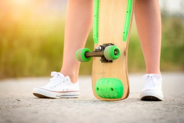 Menina adolescente anônima com skate, imagem com sunflare — Fotografia de Stock