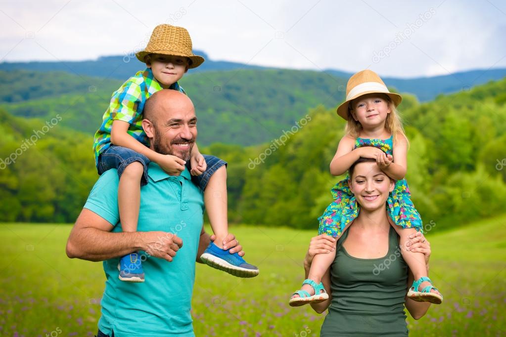 Parents giving piggyback ride to children, happy family time concept