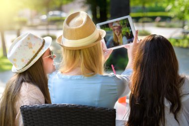 Dijital tablet ile bir selfie alarak üç çekici hippi kız arkadan görünüm