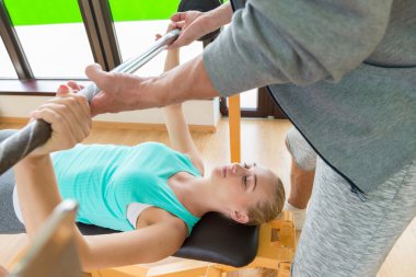 Genç kadın eğitmen ile spor salonunda bir halter kaldırma