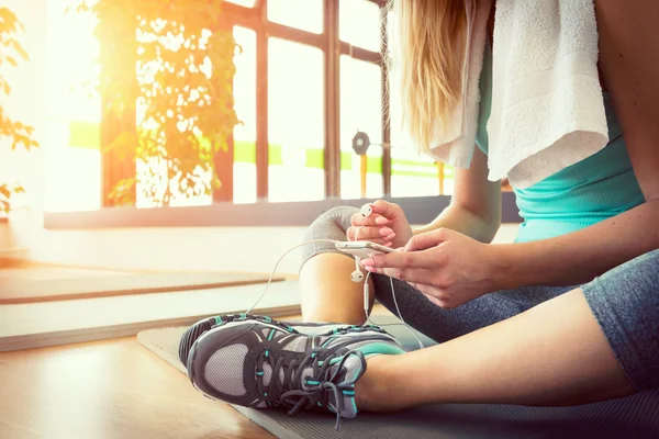 Aantrekkelijke blonde vrouw met slimme telefoon, rust na training van de gymnastiek — Stockfoto