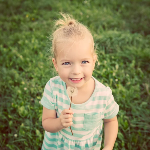 Adorable little blond girl with dandelion flower. Happy kid having fun outdoors — Stock Photo, Image