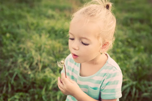 Чарівна маленька блондинка з квіткою кульбаби. Щаслива дитина розважається на відкритому повітрі — стокове фото