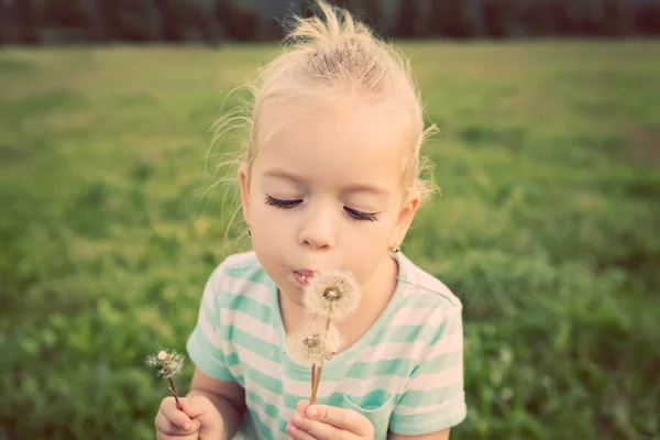 Menina loira adorável com flor de dente de leão. Criança feliz se divertindo ao ar livre — Fotografia de Stock