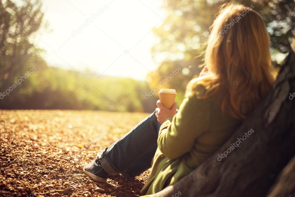 Autumn concept, anonymous woman enjoying takeaway coffee cup on sunny cold fall day