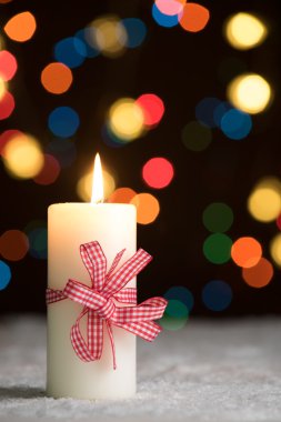 Karda defocussed peri ışıkları, bokeh arka planda, neşeli Noel arka plan boşaltmak ile kırmızı yay ile yanan mum