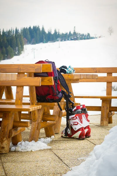 Ski boots, glowes and a backpack in an outdoor bar in a ski resort — Stock Photo, Image