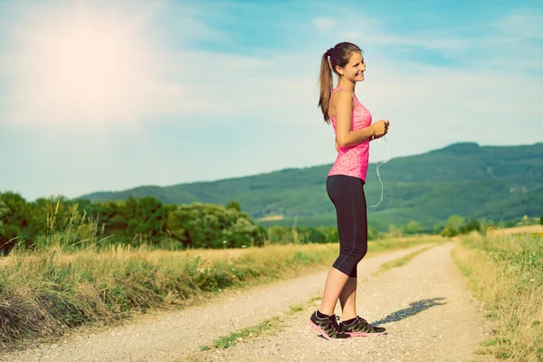 Attractive female runner holding headphones, ready for her workout — Stock Photo, Image