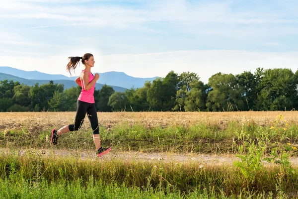 Aantrekkelijke jonge vrouwelijke joggen in platteland — Stockfoto