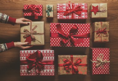 Woman organising beautifuly wrapped vintage christmas presents on wooden background, image with haze, view from above clipart