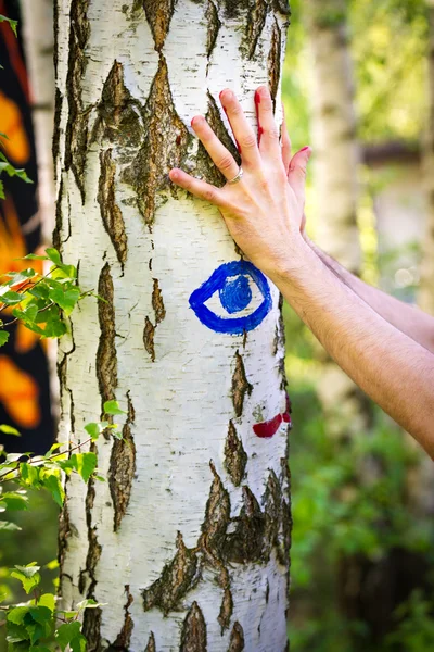 Person macht farbenfrohe Handabdrücke an einer Birke — Stockfoto
