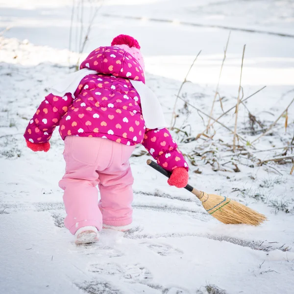 可爱的小女孩，玩一把扫帚，外面下雪的冬天白天 — 图库照片