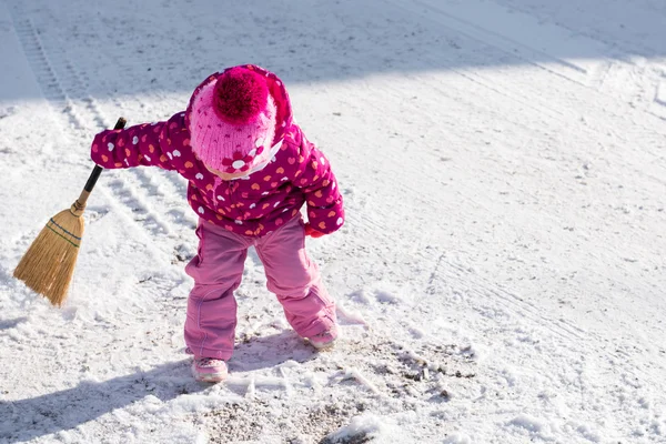 Cute dziewczynka gra z miotłą poza podczas dnia mroźną zimę — Zdjęcie stockowe