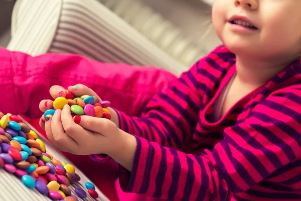 Adorable niña preescolar jugando con dulces —  Fotos de Stock