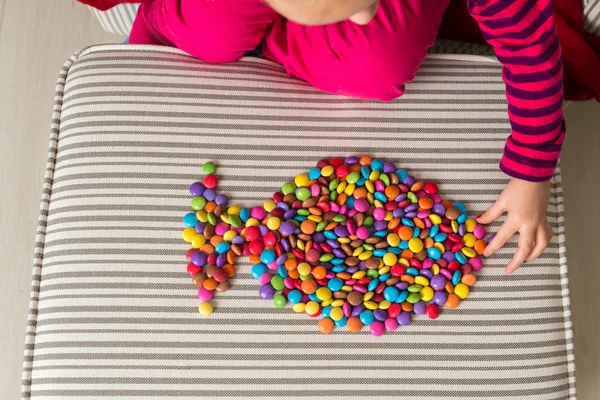 Anonymní školka dívka si hraje s barevné sladkosti — Stock fotografie