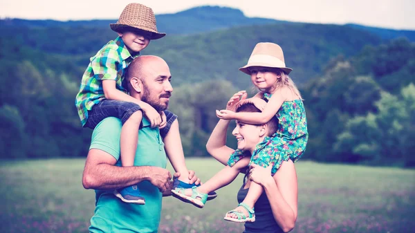 Padres dando paseo a cuestas a los niños, feliz concepto de tiempo familiar — Foto de Stock