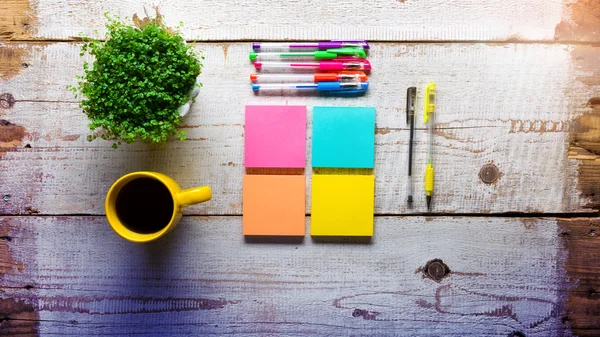 Retro white wooden table with empty colorful sticky notes, different gel pens and cup of coffee — Stock Photo, Image