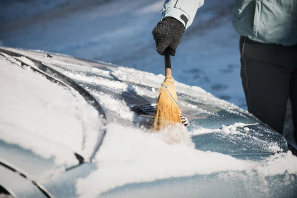 Transporte, inverno, clima, pessoas e conceito de veículo mulher limpando neve de seu carro com uma vassoura — Fotografia de Stock