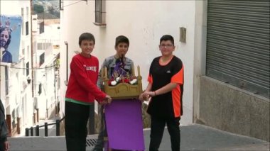 Alora, İspanya - 21 Nisan 2019: Üç çocuk Kutsal Cuma tahtının küçük bir versiyonunu köy caddesinde taşıyordu