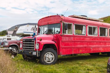 Kızıl okul otobüsü İzlanda 'da bir otoparka park edilmiş.