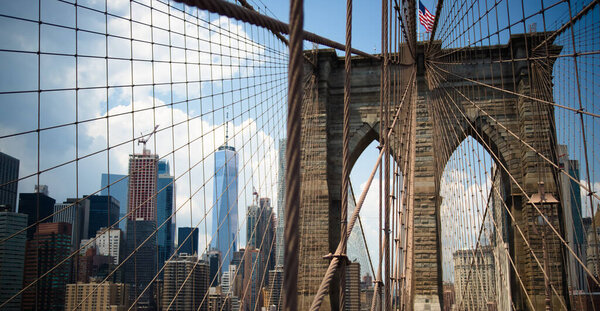 Brooklyn bridge american flag above bridge cables and stones. Brooklyn, New-York, United States