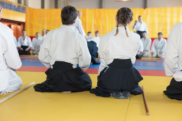 Pessoas em quimono e hakama sentadas em tatami em treinamento de artes marciais — Fotografia de Stock