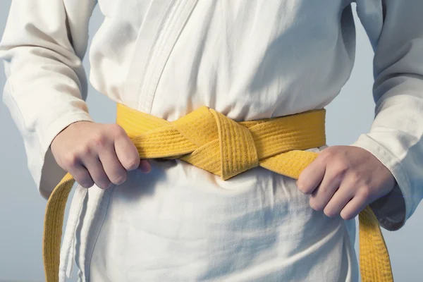 Mãos apertando cinto amarelo em uma adolescente vestida de quimono — Fotografia de Stock