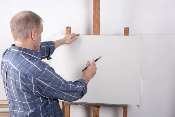 Un artiste en studio réfléchissant devant une toile blanche — Photo