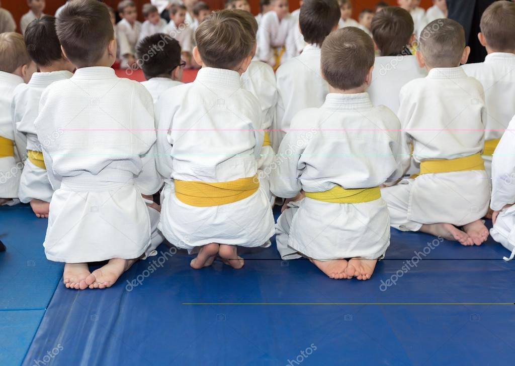 Children in kimono sitting on tatami on martial arts seminar