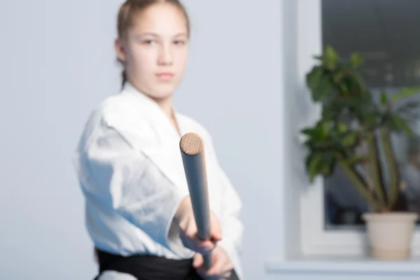 A girl in black hakama standing in fighting pose with wooden jo stick. Selective focus — Stock Photo, Image