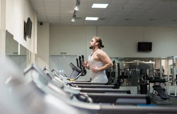 Muž běží na běžeckém pásu v tělocvičně — Stock fotografie
