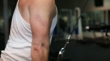Güçlü bir adam, bir spor salonunda triceps pompalama vücut geliştirmeci