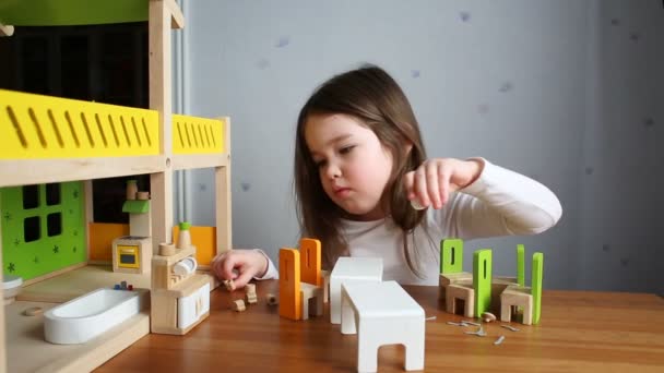 Una linda chica jugando con una casa de muñecas — Vídeos de Stock