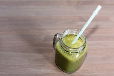 Tüp ahşap bir masa üzerinde mason kavanoza yeşil smoothie