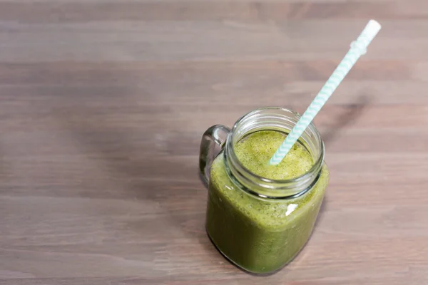 Green smoothie in mason jar with tube on a wooden table — Stock Photo, Image
