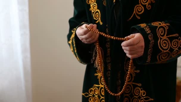 Un vecchio in abito nazionale che prega con perline rosario in mano — Video Stock