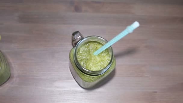 在罐子里，用木制的桌子上管绿色果汁 — 图库视频影像