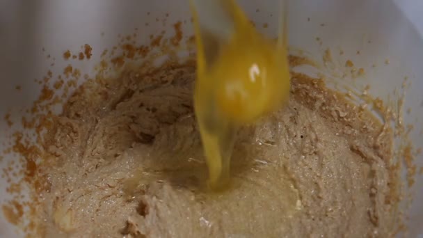 Putting eggs into a dough in a white bowl — Stock Video