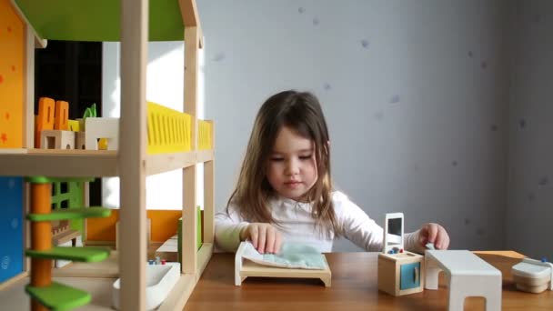 Een schattig meisje speelt met een poppenhuis — Stockvideo