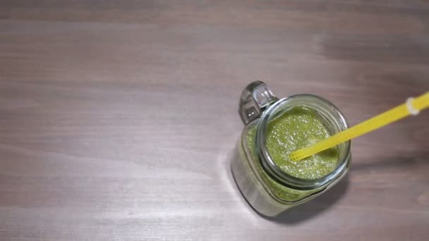 Green smoothies in mason jars with tubes on a wooden table — Stock Video