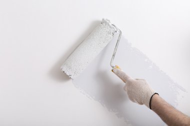 Bir duvar boya silindiri ile boyama ressam kolu yakın çekim