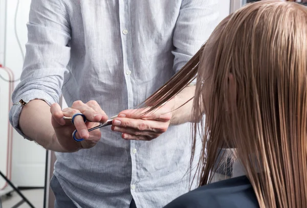 Ein Friseur, der einer blonden Kundin eine Frisur schneidet — Stockfoto