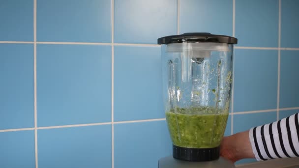 Κάνοντας πράσινο υγιεινό smoothie σε ένα γυάλινο βάζο στο μπλέντερ στο σπίτι στην κουζίνα — Αρχείο Βίντεο